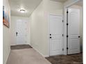 Inviting hallway with carpet, tile flooring, and white doors at 1868 Homestead Dr, Fort Lupton, CO 80621