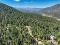 Breathtaking aerial view of the property nestled in a lush forest with mountain views at 33884 Bergen View Trl, Evergreen, CO 80439