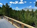 Scenic view from the back deck features a lush forest and distant mountains, ideal for relaxation at 33884 Bergen View Trl, Evergreen, CO 80439