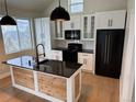 Bright kitchen features white cabinets, black appliances, granite counters and an island with wood accents at 33884 Bergen View Trl, Evergreen, CO 80439