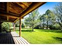 Covered porch with wooden flooring and a swing overlooks the expansive lawn and trees at 2965 Wagner St, Strasburg, CO 80136