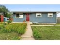 Inviting single-story home with blue siding, red door, and colorful flowers lining the walkway to the entrance at 2011 S Vallejo St, Denver, CO 80223