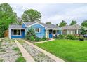 Inviting blue bungalow with mature trees, a green lawn, and a quaint front porch at 1720 Trenton St, Denver, CO 80220
