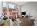 Bright, open living space featuring exposed brick, tall windows with city views, and hardwood floors at 720 16Th St # 306, Denver, CO 80202