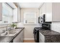 Well-lit kitchen featuring modern appliances, marble countertops, and white cabinets at 2235 W 46Th Ave, Denver, CO 80211