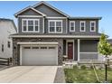 Charming two-story home featuring a gray exterior, stone accents, a two-car garage, and a cozy front porch at 1373 E Witherspoon Dr, Elizabeth, CO 80107