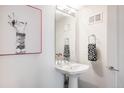 Stylish powder room featuring a pedestal sink, decorative towels, and a unique art piece at 3308 W 17Th Ave, Denver, CO 80204