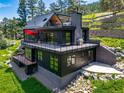 Beautiful modern home featuring a spacious outdoor deck, sleek design, and hillside views surrounded by lush greenery at 365 Bow Mountain Rd, Boulder, CO 80302