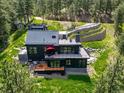 Beautiful hillside home boasts a deck and patio spaces and unique architecture, all surrounded by lush greenery and trees at 365 Bow Mountain Rd, Boulder, CO 80302