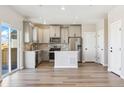Modern kitchen featuring stainless appliances, an island, and sleek wood flooring at 17881 East 94Th Ave, Commerce City, CO 80022