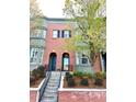 Attractive red brick townhome with bay windows, complemented by mature trees and landscaped garden at 2958 N Xenia St, Denver, CO 80238