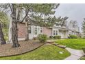 Inviting exterior view of a home with mature trees, green lawn, and partial brick facade at 5404 W Canyon Trl # C, Littleton, CO 80128