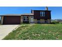 Charming home with a brick and wood exterior, complemented by a well-manicured front yard and an attached two car garage at 275 Mckinley Dr, Bennett, CO 80102