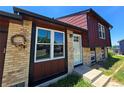 Inviting front entrance featuring a decorative wreath, complemented by brick accents and updated windows at 275 Mckinley Dr, Bennett, CO 80102