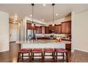 Kitchen island features seating, pendant lighting, and stainless-steel appliances at 6916 Crestop Pl # F, Parker, CO 80138
