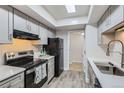 Well-lit kitchen with modern gray cabinets, skylight, black appliances and light countertops, creating a functional cooking space at 3550 S Harlan St # 177, Denver, CO 80235