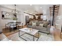 Open-concept living room with modern decor, hardwood floors, and a view of the adjacent dining area and kitchen at 5423 S Prince St # B, Littleton, CO 80120