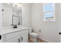 Clean bathroom features white vanity with black hardware and fixtures, with neutral floor and natural light at 833 Alpine Ridge St, Erie, CO 80516