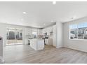 Open-concept kitchen boasts white cabinets, an island, stainless steel appliances, and sliding door access to outdoor at 833 Alpine Ridge St, Erie, CO 80516