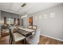 Open dining room with hardwood floors, modern chandelier, and decor art pieces at 2602 E 145Th Ave, Thornton, CO 80602
