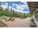 Expansive deck showcasing views of the surrounding woods. Features built-in seating and an outdoor grill at 1774 Upper Bear Creek Rd, Evergreen, CO 80439