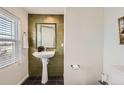 Powder room with a pedestal sink, olive green tiled accent wall, and modern fixtures at 9300 E Florida Ave # 1101, Denver, CO 80247