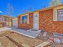 Classic brick home featuring a secure front entrance with a storm door and tidy front yard landscaping at 2675 S Carson Way, Aurora, CO 80014