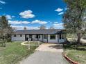 Charming single story home with white siding, black trim, front porch, and well manicured lawn at 1428 S County Road 23E, Berthoud, CO 80513