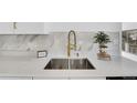 A modern kitchen features a stainless steel sink with a brass faucet and marble backsplash at 4642 Everett Ct, Wheat Ridge, CO 80033