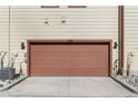 Spacious two-car garage featuring a brown door and exterior lighting at 11294 Bella Vita Dr, Broomfield, CO 80020