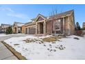 Exterior elevation of a home featuring a two-car garage, stone accents, and a welcoming front porch at 160 Pipit Lake Way, Erie, CO 80516