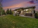 Spacious backyard with a covered patio, green lawn, mature trees, and an inviting hot tub at 19379 W 57Th Pl, Golden, CO 80403