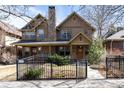 Inviting two-story home featuring a stone chimney, detailed trim, and a black fence at 2042 S Clayton St, Denver, CO 80210