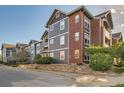 Exterior view of multi-story condo featuring gray siding, brick accents, and well-maintained landscaping at 14221 E 1St Dr # 303, Aurora, CO 80011
