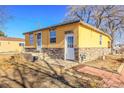 Exterior of the property featuring a yellow facade, stone accents, and well-maintained landscaping at 724 County Road 37, Brighton, CO 80603