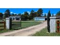 View of the entrance gate leading to the home with lush greenery and trees surrounding the property at 40477 Ferns Rd, Elizabeth, CO 80107