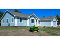 Beautiful blue house with a green lawn mower in the front yard on a sunny day at 40477 Ferns Rd, Elizabeth, CO 80107