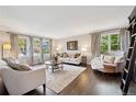 Elegant living room with hardwood floors, neutral-toned furniture, and ample natural light from the large windows at 11453 E Orchard Pl, Englewood, CO 80111