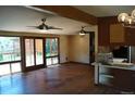 Open living room with hardwood floors, ceiling fans, and access to an outdoor deck at 6775 S Sherman St, Centennial, CO 80122