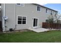 Back of house with lawn, patio, and sliding glass door, windows, and neutral siding at 5546 S Quemoy Cir, Aurora, CO 80015
