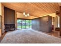 Bright living room with a stone fireplace, wood ceilings, and sliding glass doors to the outside at 3650 Chimayo Rd, Littleton, CO 80123