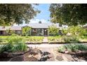 View of a well-maintained single-story home with professional landscaping under a canopy of mature shade trees at 1185 Glencoe St, Denver, CO 80220