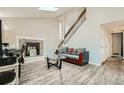 Living room featuring tall ceilings, a fireplace, wood-look floors, and an open staircase at 1946 Ensenada St, Aurora, CO 80011
