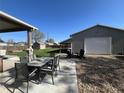 Inviting backyard patio area with outdoor dining set, fire pit, a lush lawn, and a shop building at 504 Elizabeth Ave, Platteville, CO 80651