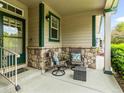Covered front porch features stone accents, seating and a view of the surrounding neighborhood at 1836 S Kendall Ct, Lakewood, CO 80232