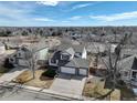 Aerial view of the home showing a well-maintained lawn, three-car garage, and neighborhood at 7036 Orion Ln, Arvada, CO 80007