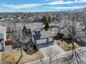 An aerial view showcases the home's setting within a mature neighborhood with views of the distant mountains at 7036 Orion Ln, Arvada, CO 80007