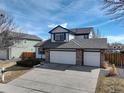 Charming two-story home featuring a three car garage with stone accents and a well-maintained front yard at 7036 Orion Ln, Arvada, CO 80007