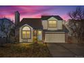 Charming two-story home featuring a well-maintained yard and attached two-car garage at dusk at 10407 Strasburg Way, Parker, CO 80134