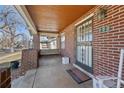 A brick porch with a wood ceiling, decorative security door, and swing in the background at 772 Garfield St, Denver, CO 80206